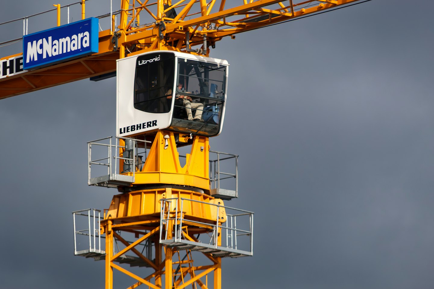 Operator dźwigu pracuje przy sterach w kabinie żurawia wieżowego.